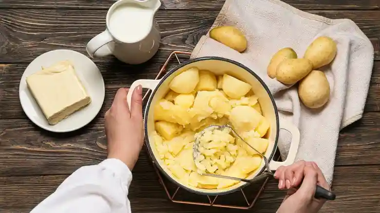 A landscape image showcasing various potato-based dishes suitable for people with braces, including creamy mashed potatoes, cheesy potato bake, and soft boiled potatoes arranged on a rustic wooden table with warm lighting.