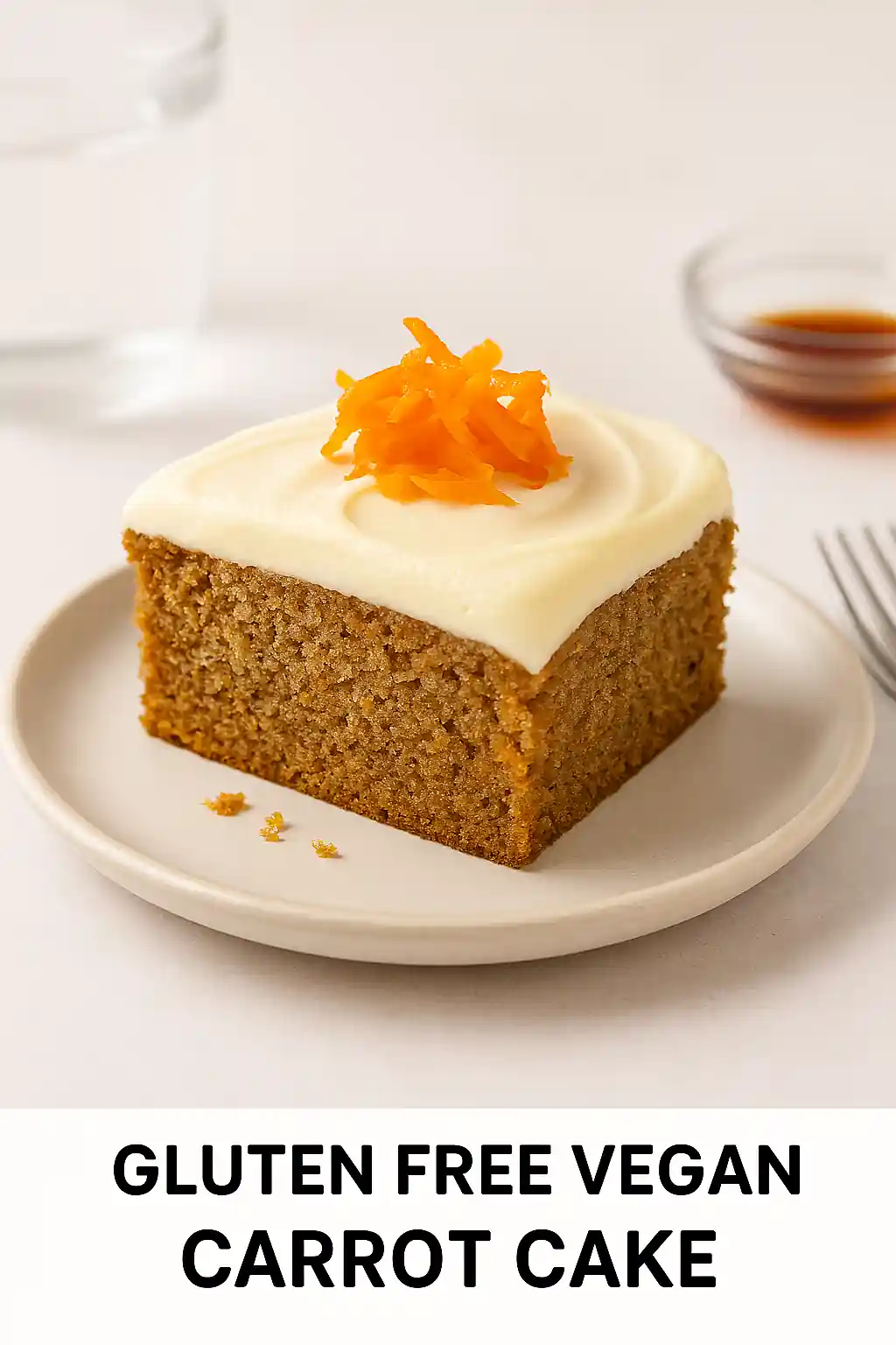 Gluten free vegan carrot cake slice with coconut frosting and carrot garnish, plated in bright natural kitchen lighting.